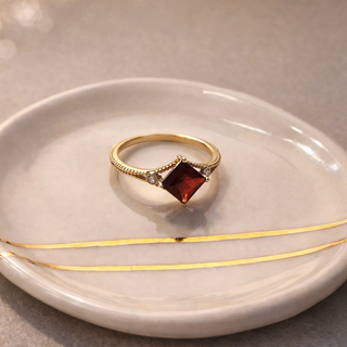 Princess Cut Garnet Ring with Diamond Accents on a porcelain plate