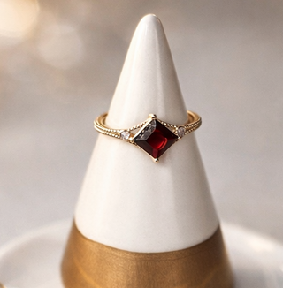 Decorative ring holder with gold and white design on a plate.