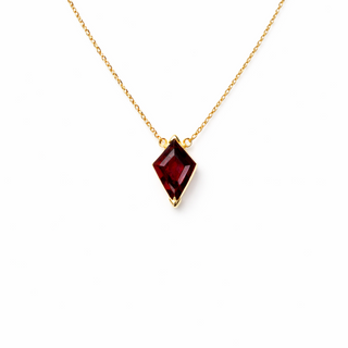 Gold necklace with a garnet gemstone pendant on a white background