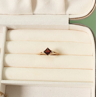 Open beige jewelry box with rings and a necklace on a light green background